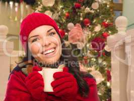 Warmly Dressed Female With Mug In Front of Decorated Christmas T