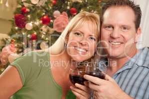 Caucasian Couple Holding Wine Glasses In Front of Decorated Chri
