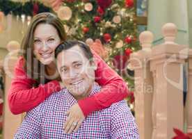 Caucasian Couple Hugging In Front of Decorated Christmas Tree.