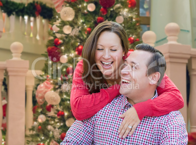 Caucasian Couple Laughing In Front of Decorated Christmas Tree.