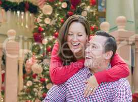 Caucasian Couple Laughing In Front of Decorated Christmas Tree.