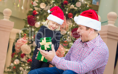Happy Young Girl and Father Wearing Santa Hats Opening Gift Box