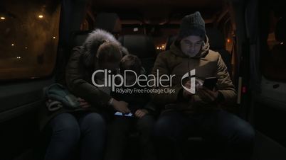 Three passengers using mobiles in minibus