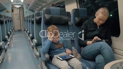 Family traveling by train and entertaining with electronics