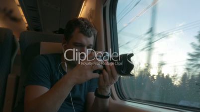 Man traveler shooting video through train window