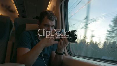 Man in train shooting footage and looking out the window