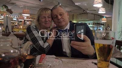 Senior family couple taking selfie in restaurant