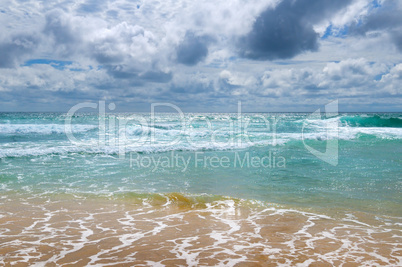 The sandy beach of the tropical ocean and the overcast sky.