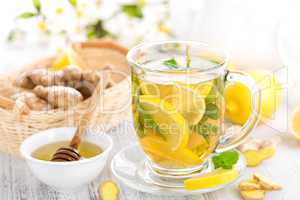 Flavored herbal tea with fresh lemon, ginger and mint leaves on white background, closeup