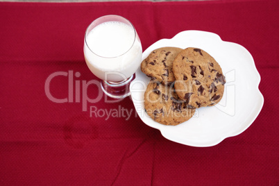 Chocolate chip cookies on a white plate with whole milk