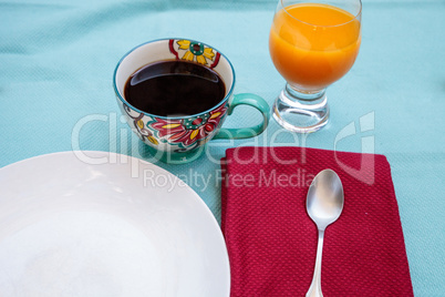 Black coffee in a colorful flower print cup with orange juice