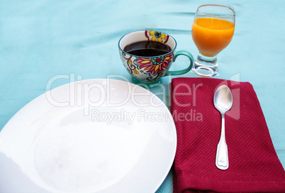 Black coffee in a colorful flower print cup with orange juice