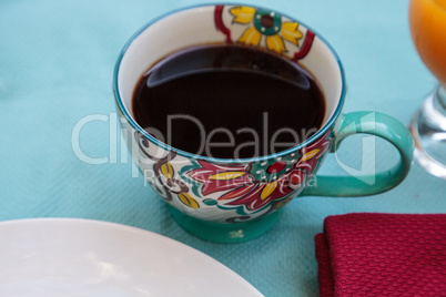 Black coffee in a colorful flower print cup with orange juice