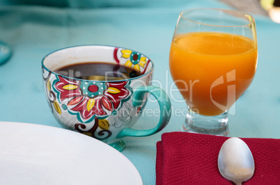 Black coffee in a colorful flower print cup with orange juice