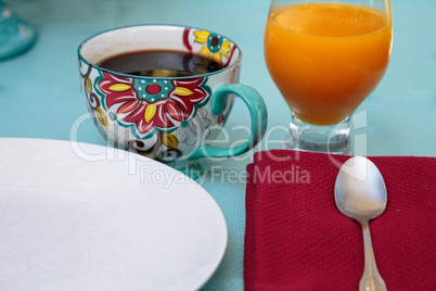 Black coffee in a colorful flower print cup with orange juice