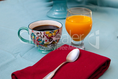 Black coffee in a colorful flower print cup with orange juice