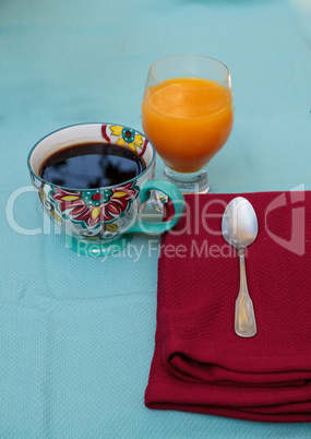 Black coffee in a colorful flower print cup with orange juice