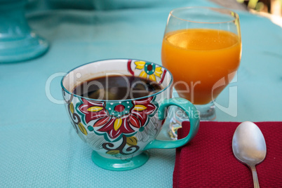 Black coffee in a colorful flower print cup with orange juice