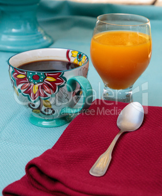 Black coffee in a colorful flower print cup with orange juice