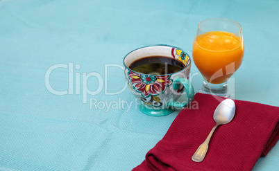 Black coffee in a colorful flower print cup with orange juice