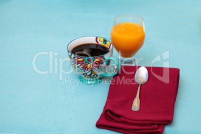 Black coffee in a colorful flower print cup with orange juice