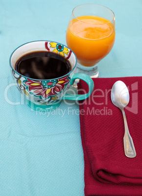 Black coffee in a colorful flower print cup with orange juice