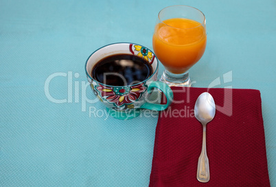 Black coffee in a colorful flower print cup with orange juice