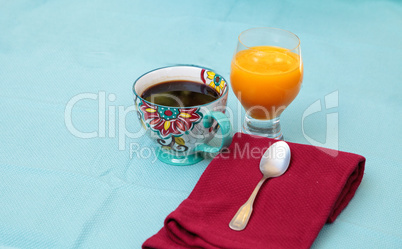 Black coffee in a colorful flower print cup with orange juice