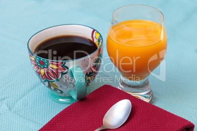 Black coffee in a colorful flower print cup with orange juice