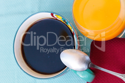 Black coffee in a colorful flower print cup with orange juice