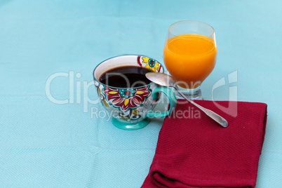 Black coffee in a colorful flower print cup with orange juice