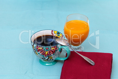 Black coffee in a colorful flower print cup with orange juice