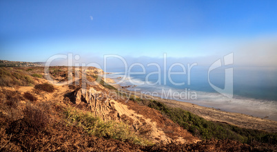 Moon in the sky as Fog drifts in over the ocean at Crystal Cove