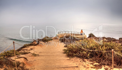 Lone man stands at a vista as Fog drifts in over the ocean at Cr