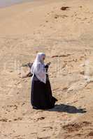 Woman in a hijab and chador dressed modestly at the beach