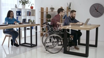 Disabled worker and colleagues working in office