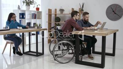 Hipster man in wheelchair working in office