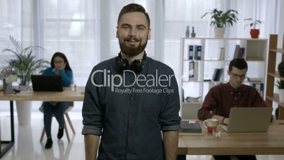 Portrait of young hipster with beard at workplace