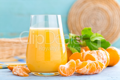 Tangerines, peeled tangerines and tangerine juice in glass. Mandarine juice and fresh fruits with leaves.