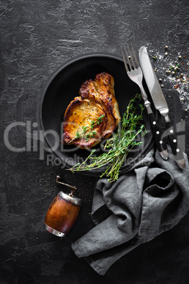 Pork meat, grilled steak on black background, top view