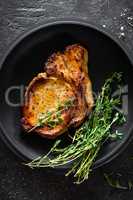 Pork meat, grilled steak on black background, top view