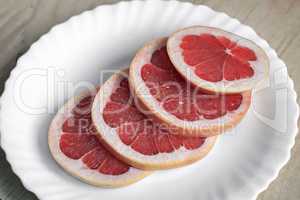 Sliced fruit of the grapefruit on the plate.