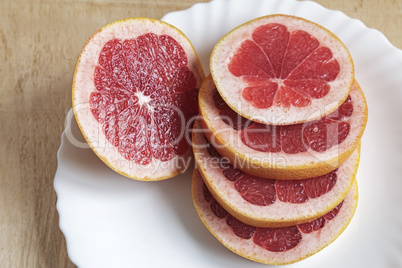 Sliced fruit of the grapefruit on the plate.