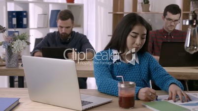 Woman working with documents and laptop in office