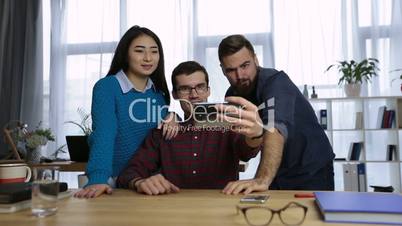 Casual colleagues taking self-portrait in office