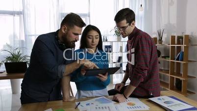 Friendly business team using tablet in office