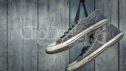 textile torn sneakers hanging from a nail on a background of blu