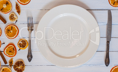 white empty dining plate with cutlery on a white wooden surface