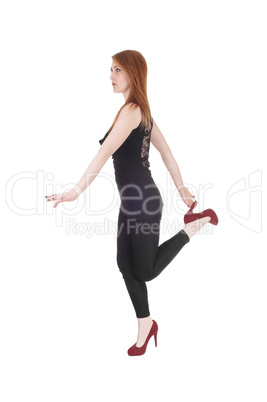 Woman standing on one leg holding heels
