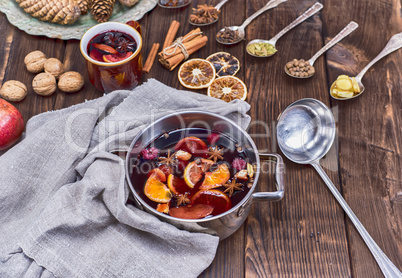 mulled wine in a saucepan and iron spoons with ingredients